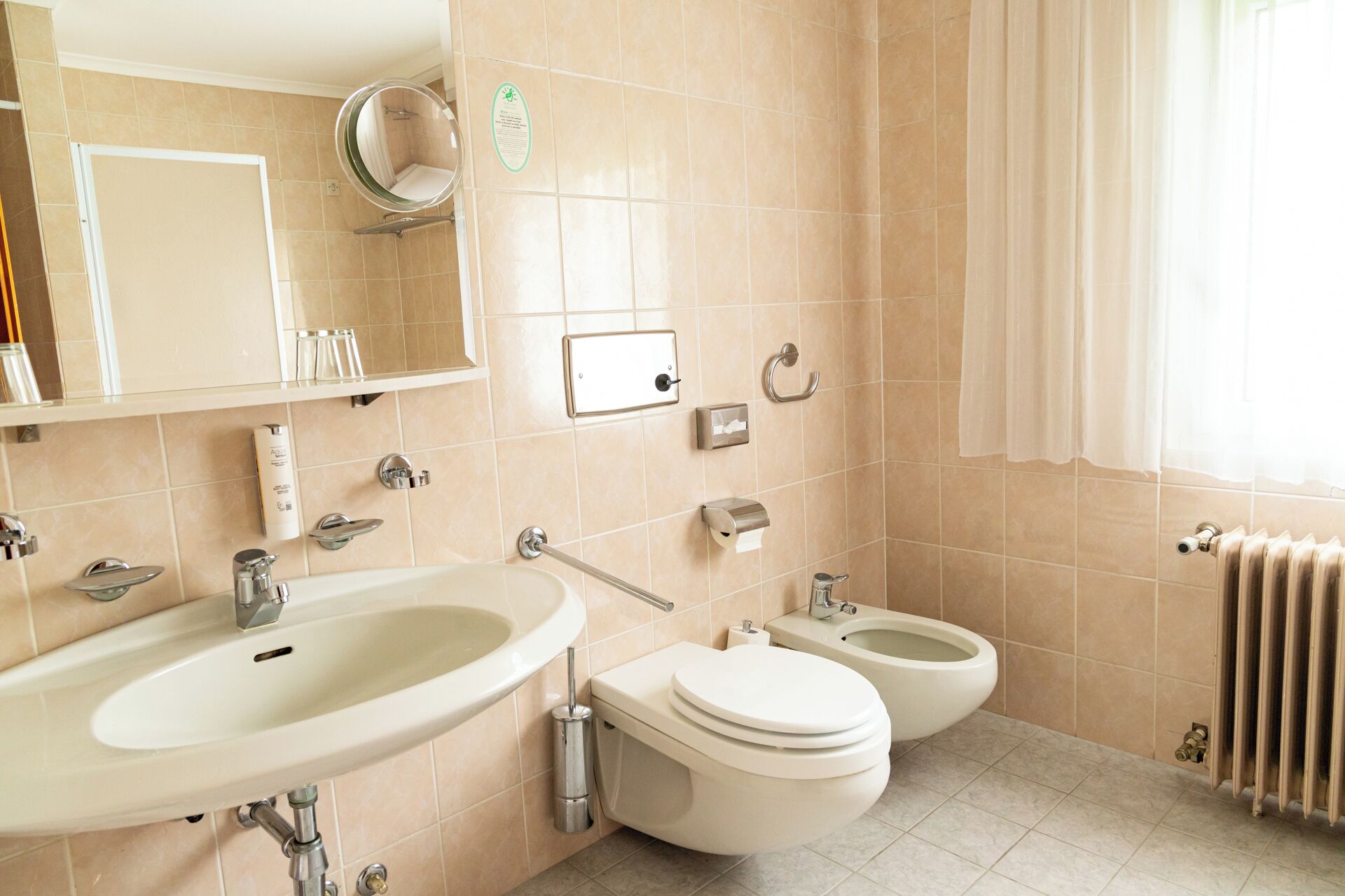 Un bagno con lavandino, water, bidet e specchio.
