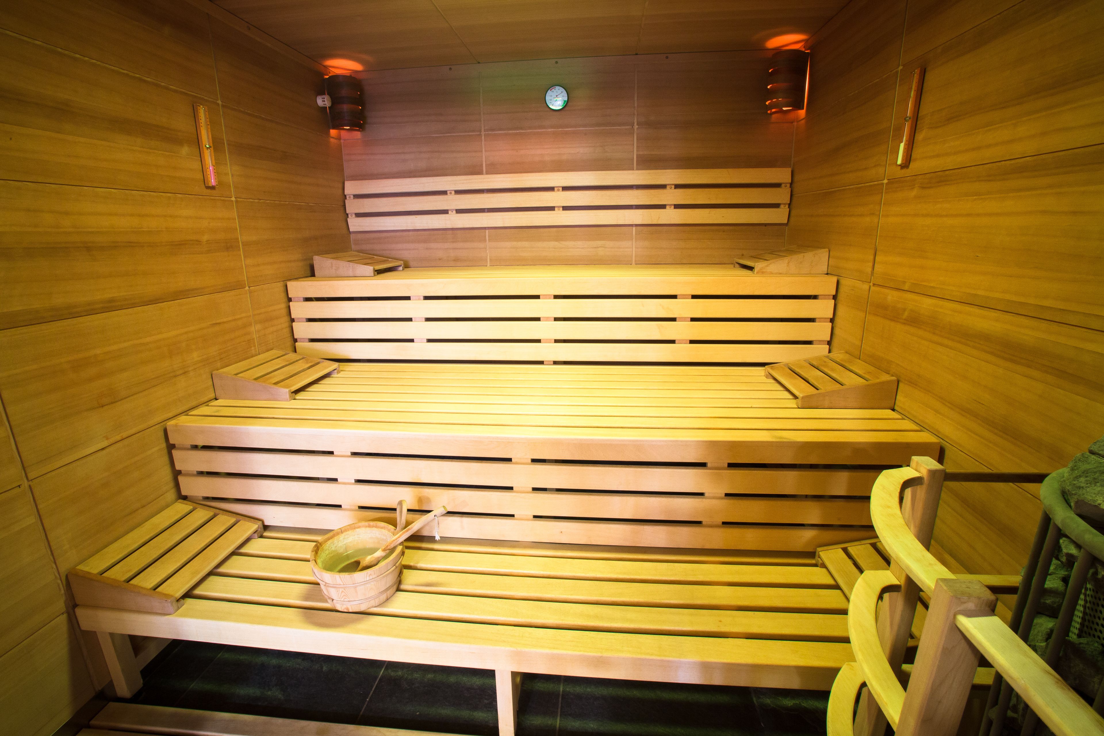 Una sauna con bancos de madera y un banco con una toalla y un cubo.