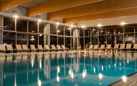 A swimming pool with lounge chairs and large windows.