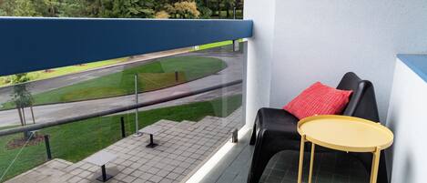 A balcony with a black sofa, a small round table, and a red pillow.