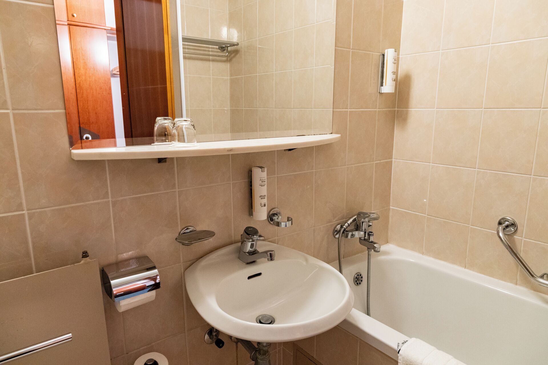 A bathroom with a white sink, a bathtub, and a mirror above the sink.