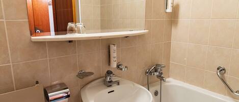 A bathroom with a white sink, a bathtub, and a mirror above the sink.