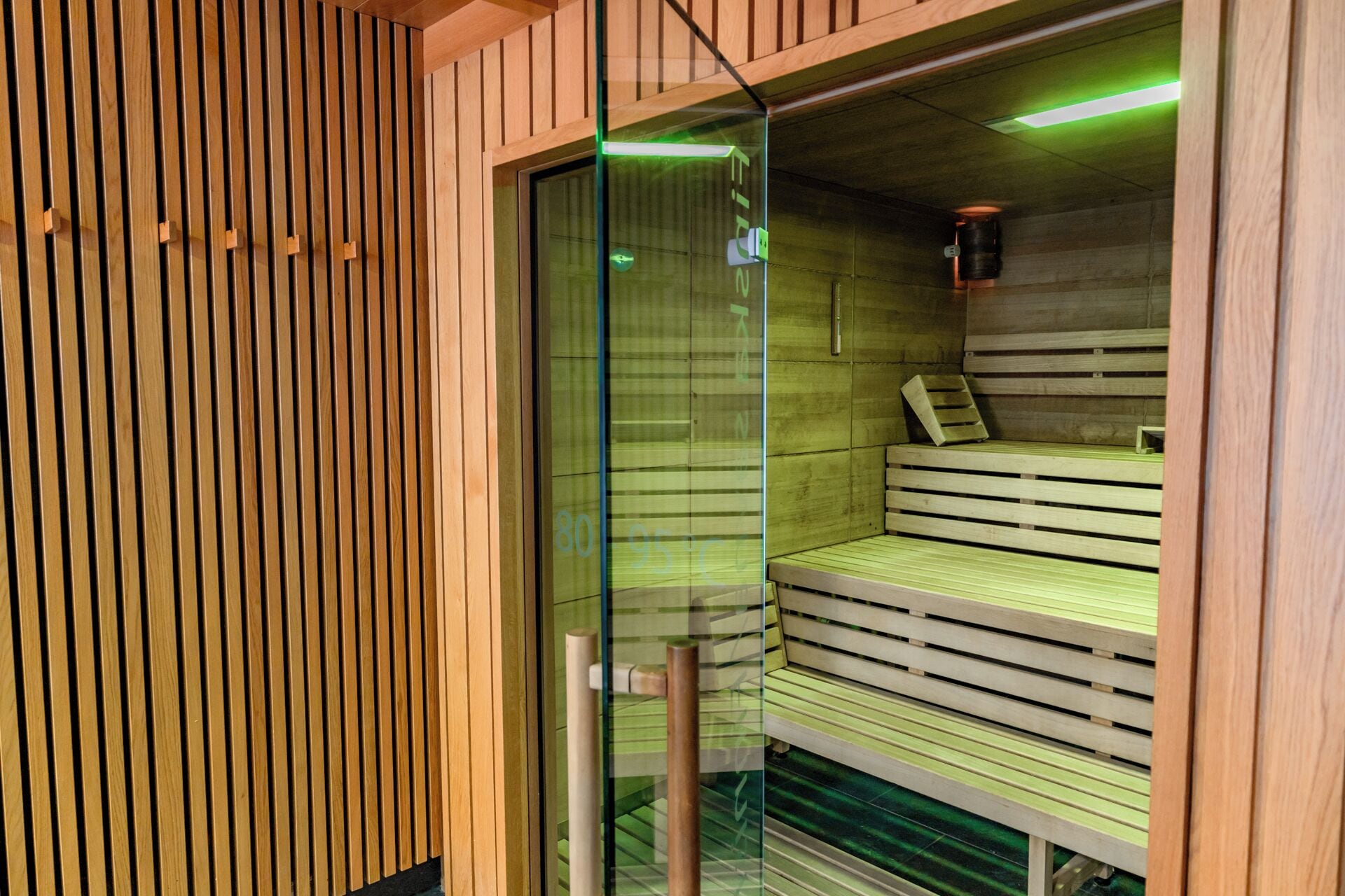 Un sauna avec des bancs en bois et une porte en verre.