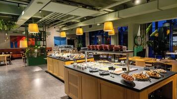 A buffet-style breakfast area with a variety of food items, wooden cabinets, and hanging pendant lights.