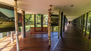A covered wooden deck with a bench, birch trees, and a view of a park. - Hotel Kristal - Terme Krka (Dolenjske Toplice)