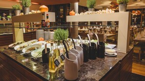 A buffet area with various food dishes, condiment bottles, and potted plants. - Hotel Kristal - Terme Krka (Dolenjske Toplice)