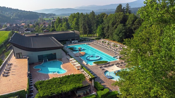Un resort con una gran piscina, tumbonas y vistas a las montañas circundantes.