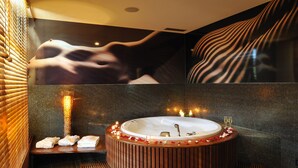 A luxurious bathroom with a freestanding bathtub, a bench, and a tiled wall. - Hotel Kristal - Terme Krka (Dolenjske Toplice)