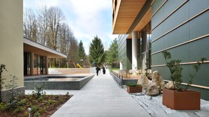 A modern building with a covered walkway, outdoor seating, and potted plants. - Hotel Kristal - Terme Krka (Dolenjske Toplice)