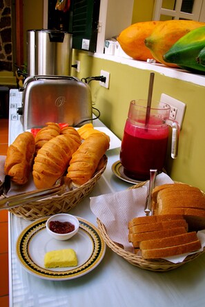 A breakfast setting with croissants, bread, a drink, and a butter dish.