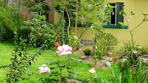Um edifício de dois andares com fachada amarela, persianas verdes e chaminé de pedra.