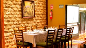 Uma sala de jantar com parede de pedra, um quadro emoldurado, um extintor de incêndio e uma lousa.