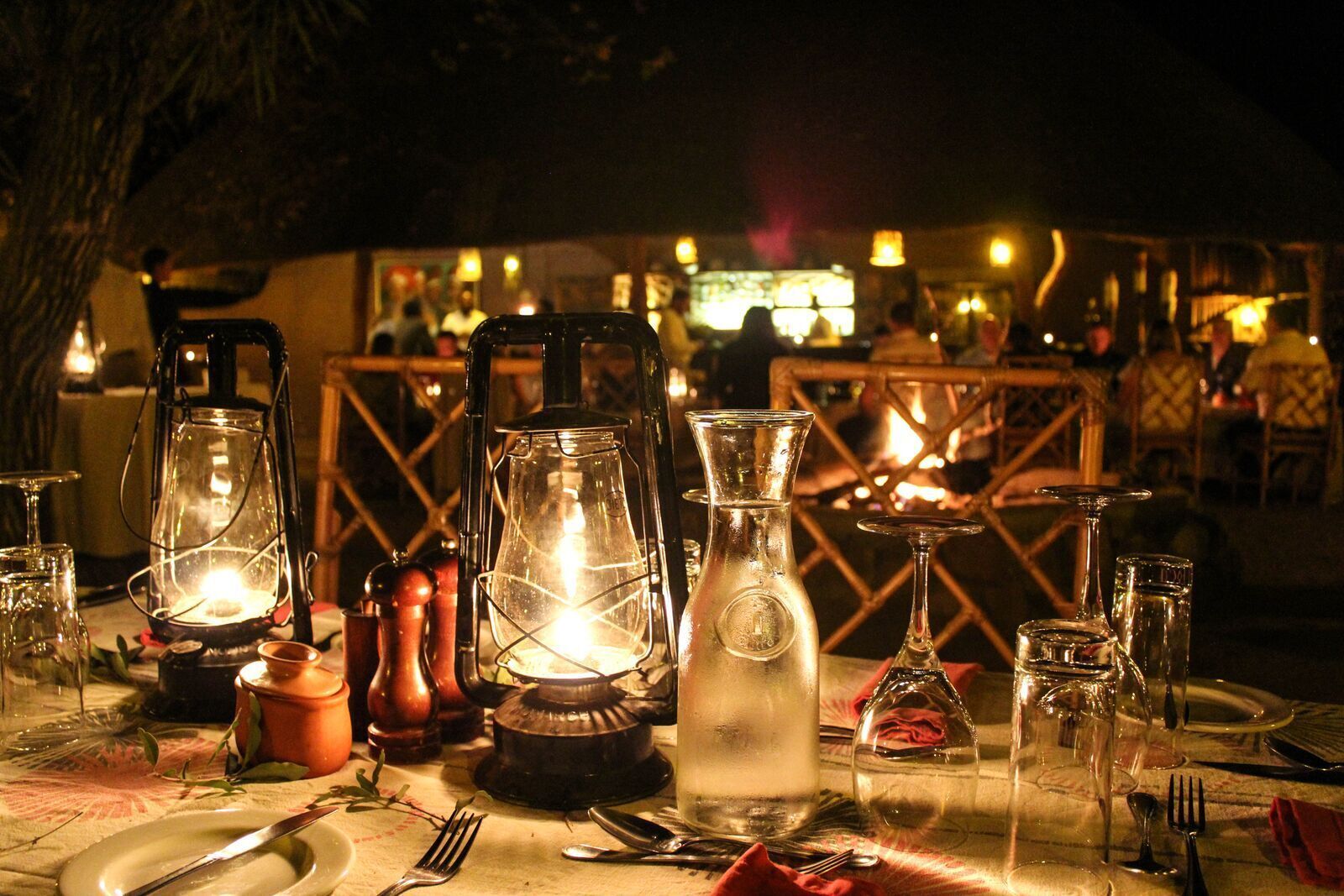 A table set for dining with lanterns, glasses, and cutlery.