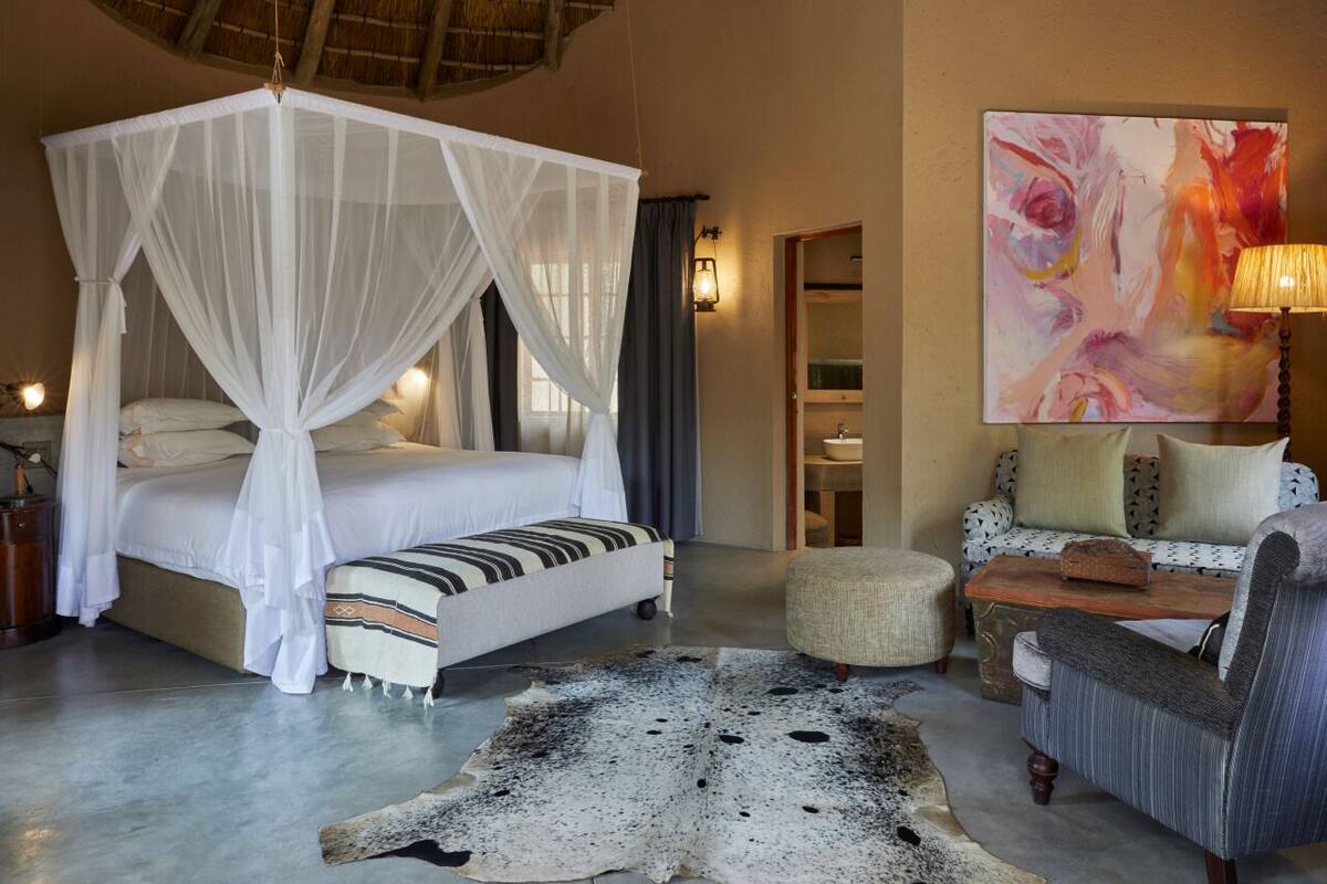 Une chambre à coucher avec un lit à baldaquin, un canapé, une table basse et un tapis.