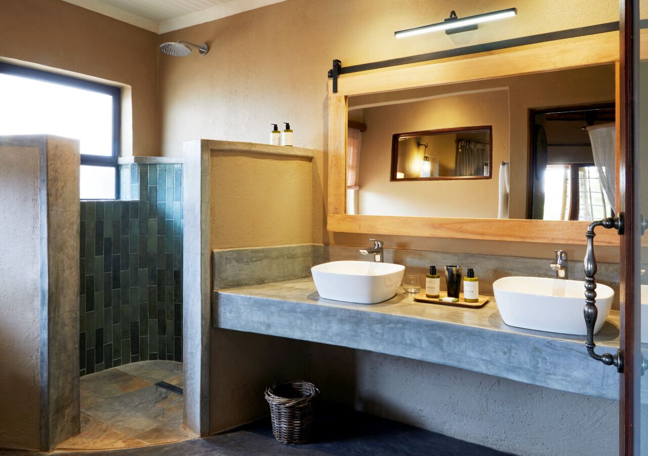 A bathroom with two sinks, a shower, and a large mirror.