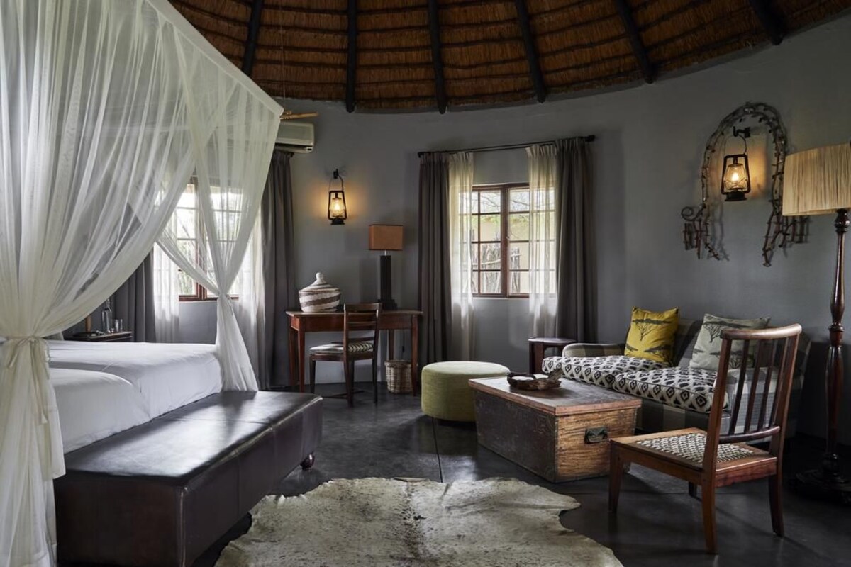 A room with a bed, a sofa, a wooden chest, and a small table.