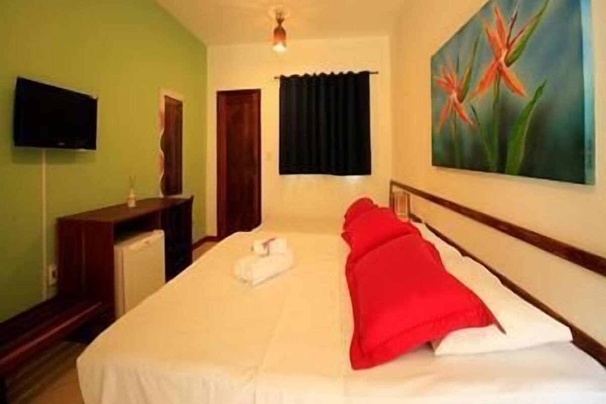 Ein Hotelzimmer mit Bett, einem Bild, einem Fernseher und einer Tür.