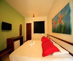 A hotel room with a bed, a painting, a TV, and a door.