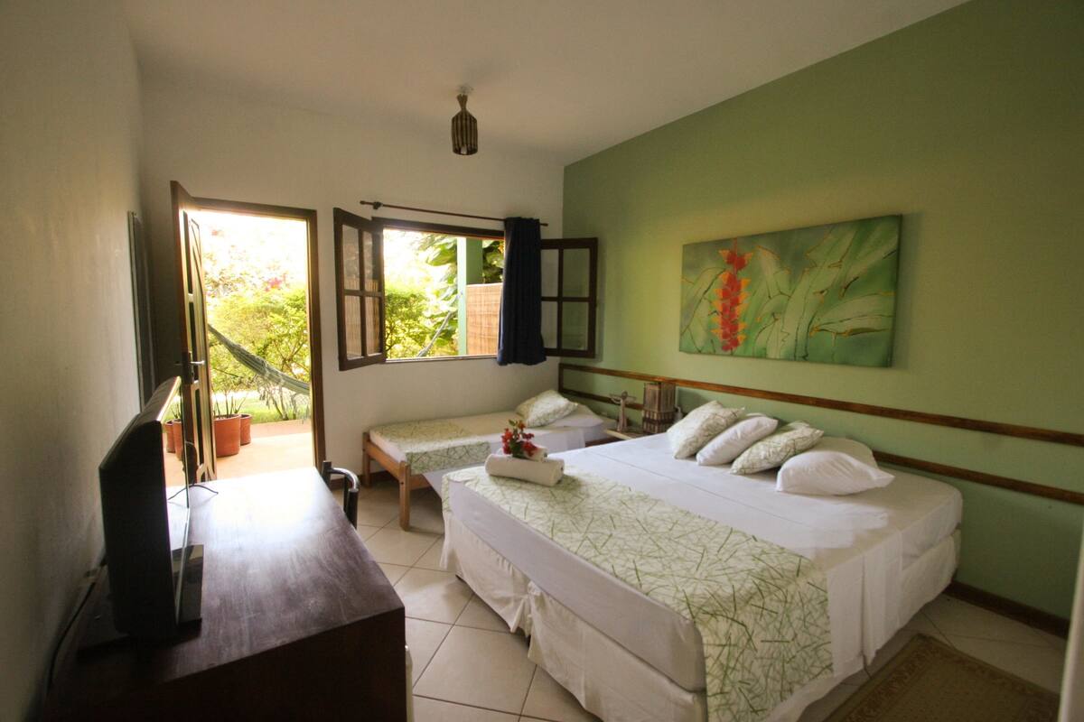 Ein Schlafzimmer mit zwei Betten, einem Fernseher und einem Balkon mit Topfpflanzen.