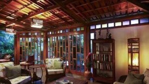 Um quarto acolhedor com móveis de madeira, uma estante de livros e grandes janelas com vista para o verde.