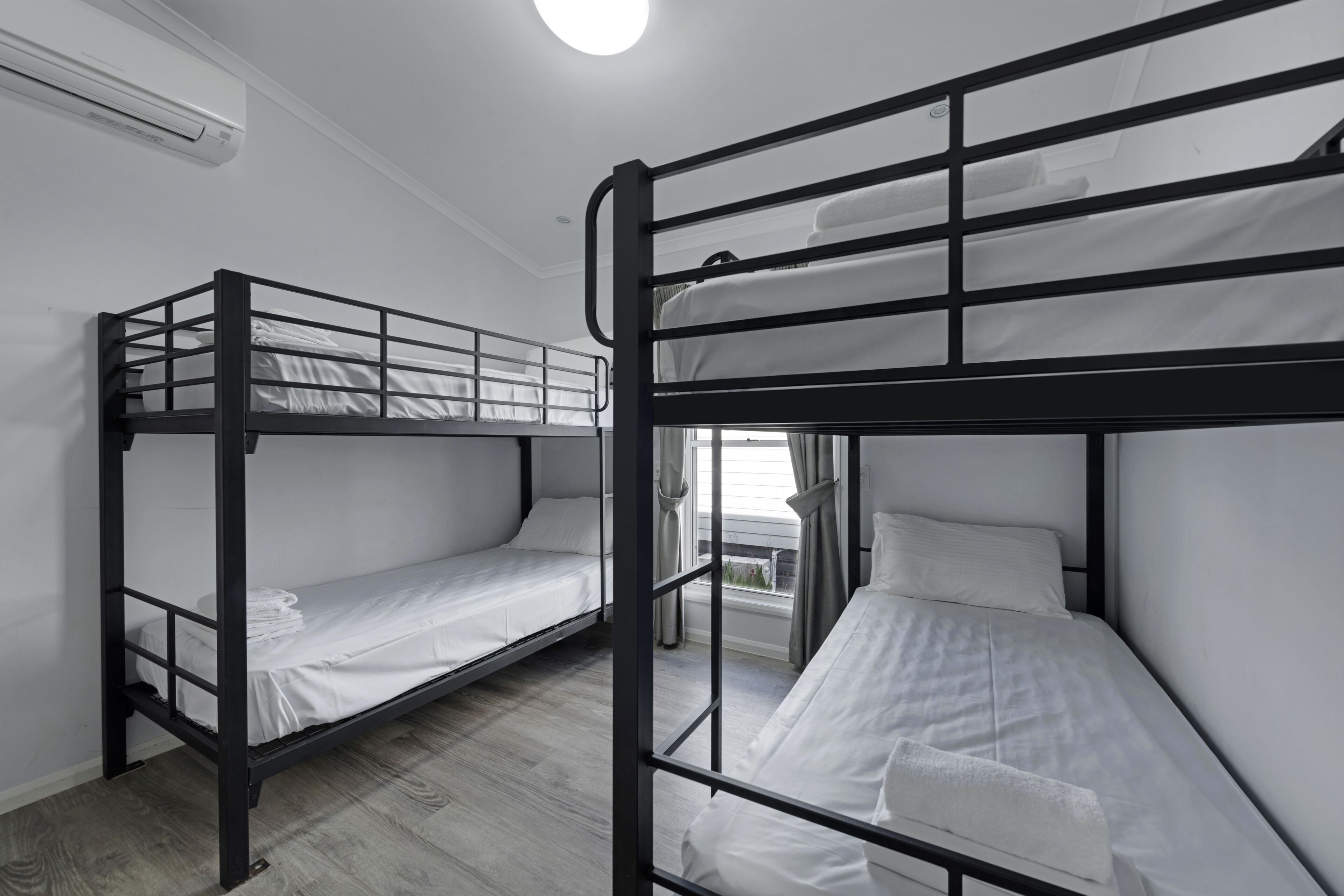 A room with two bunk beds, a window with curtains, and an air conditioning unit on the wall.