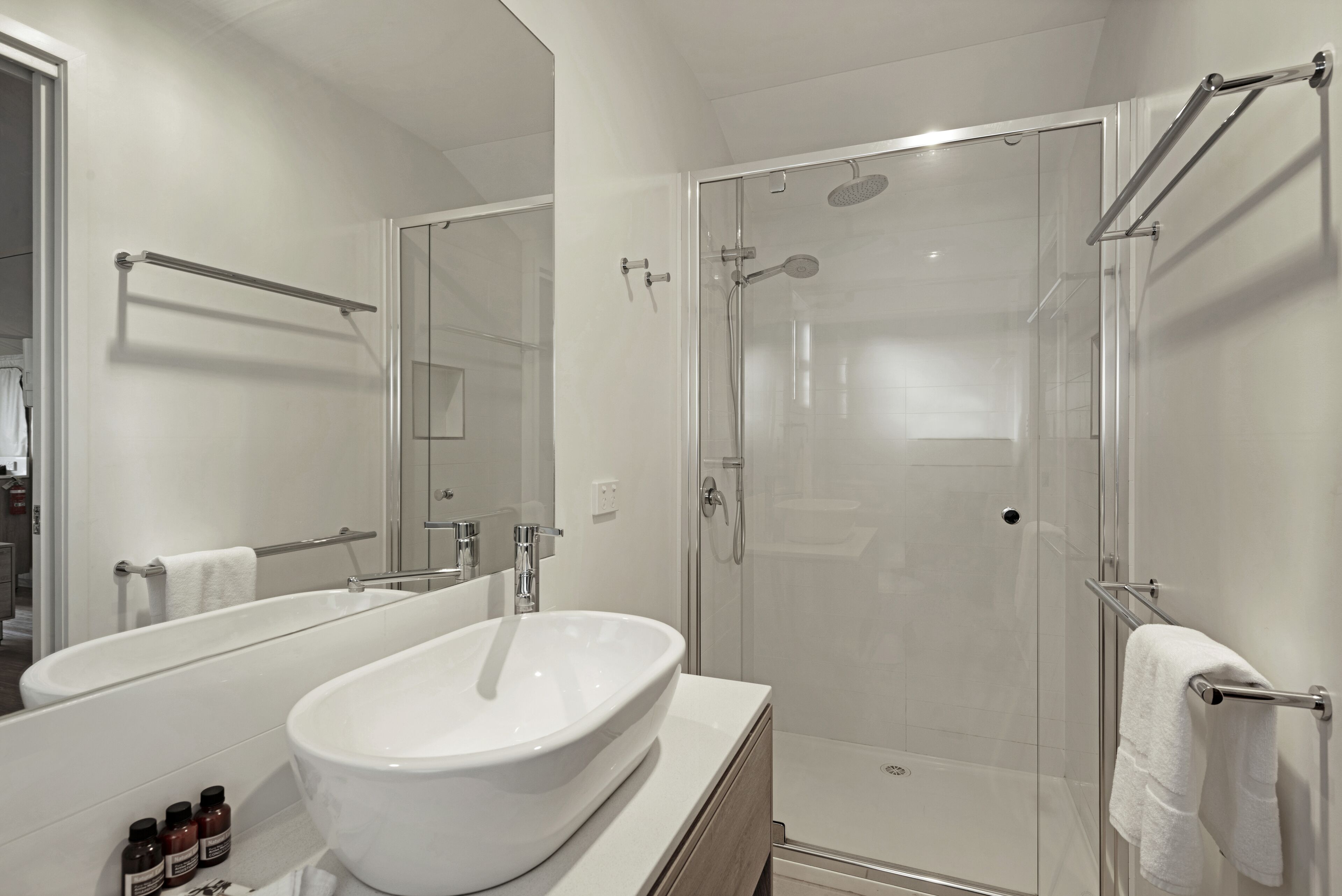 Une salle de bain moderne avec un grand lavabo blanc, une douche à parois de verre et un miroir au-dessus du lavabo.
