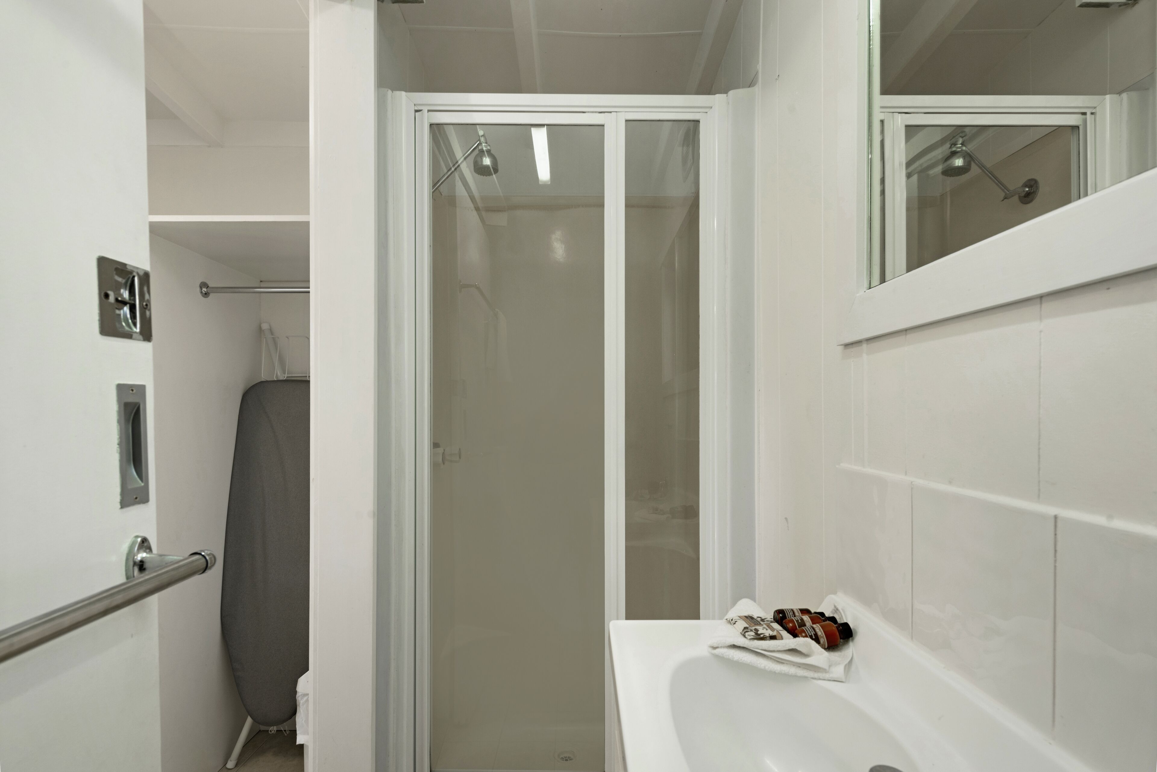 Un baño con ducha, inodoro y lavamanos con espejo.