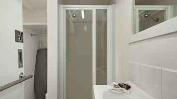 A bathroom with a shower, a toilet, and a sink with a mirror.