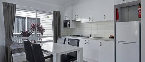 A modern kitchen with white cabinets, a stainless steel range hood, a microwave, and a Haier refrigerator.