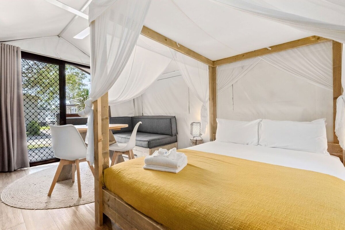 Um quarto tipo tenda com uma cama, um sofá, uma mesa e uma cadeira.