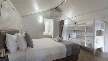 A bedroom with a bed, pillows, a bedside table, a bunk bed, and an air conditioning unit.