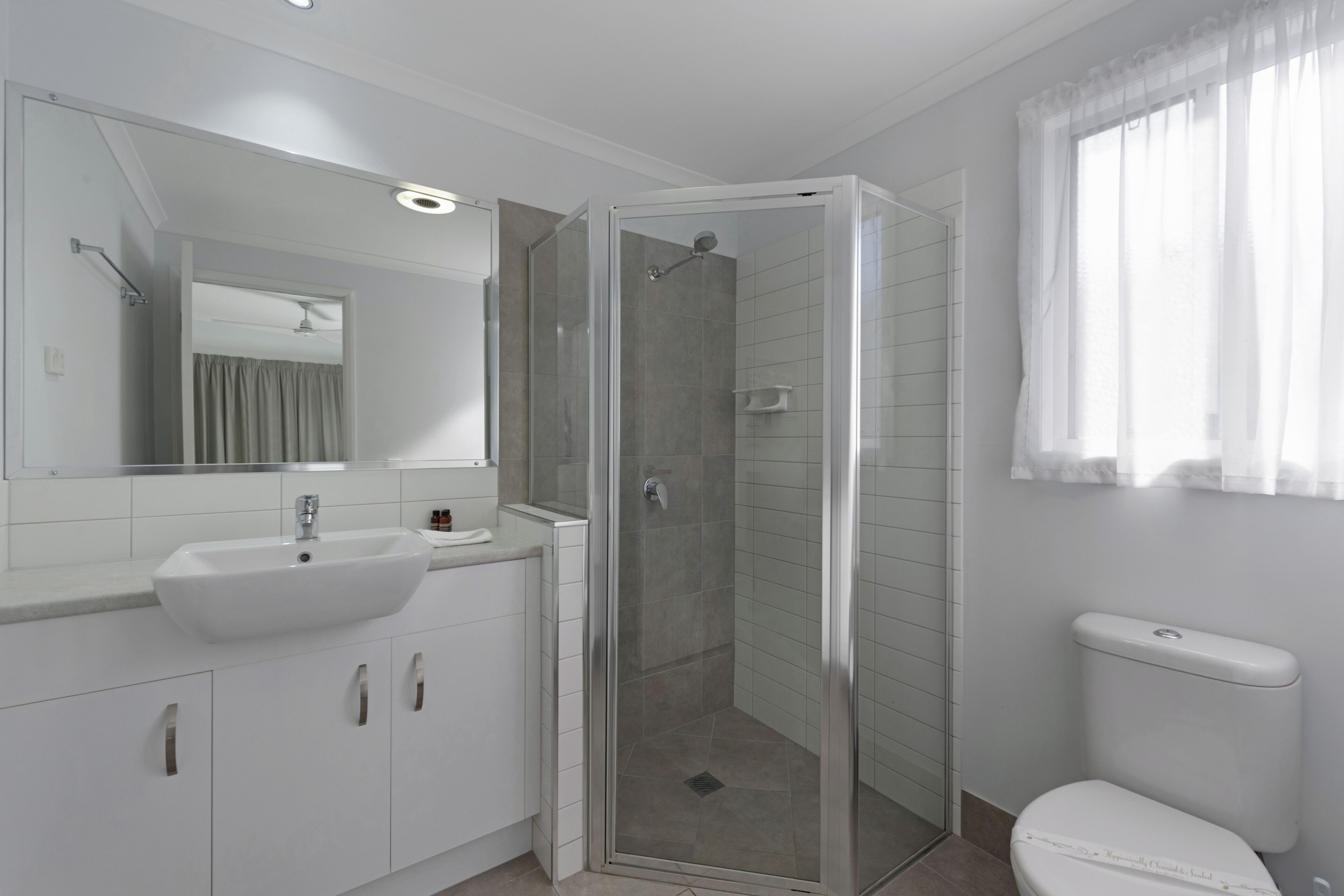 A modern bathroom with a glass-enclosed shower, a white sink, and a toilet.