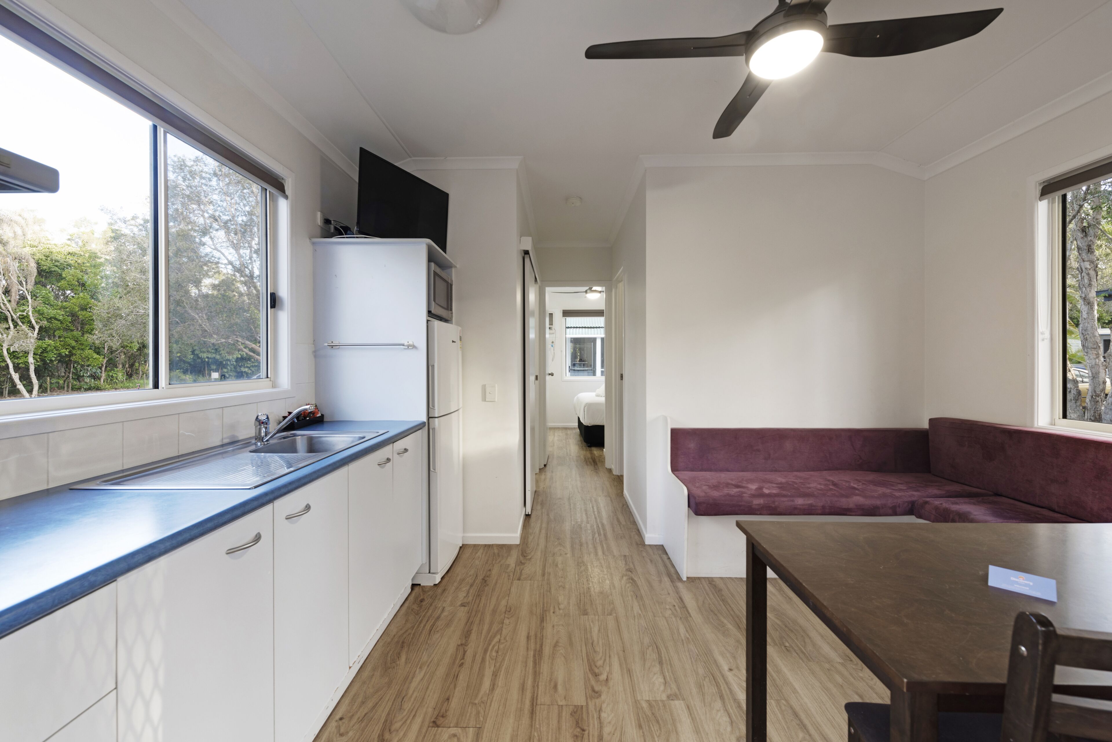Una cocina moderna con horno empotrado, un lavamanos y una zona de comedor con mesa y banco.
