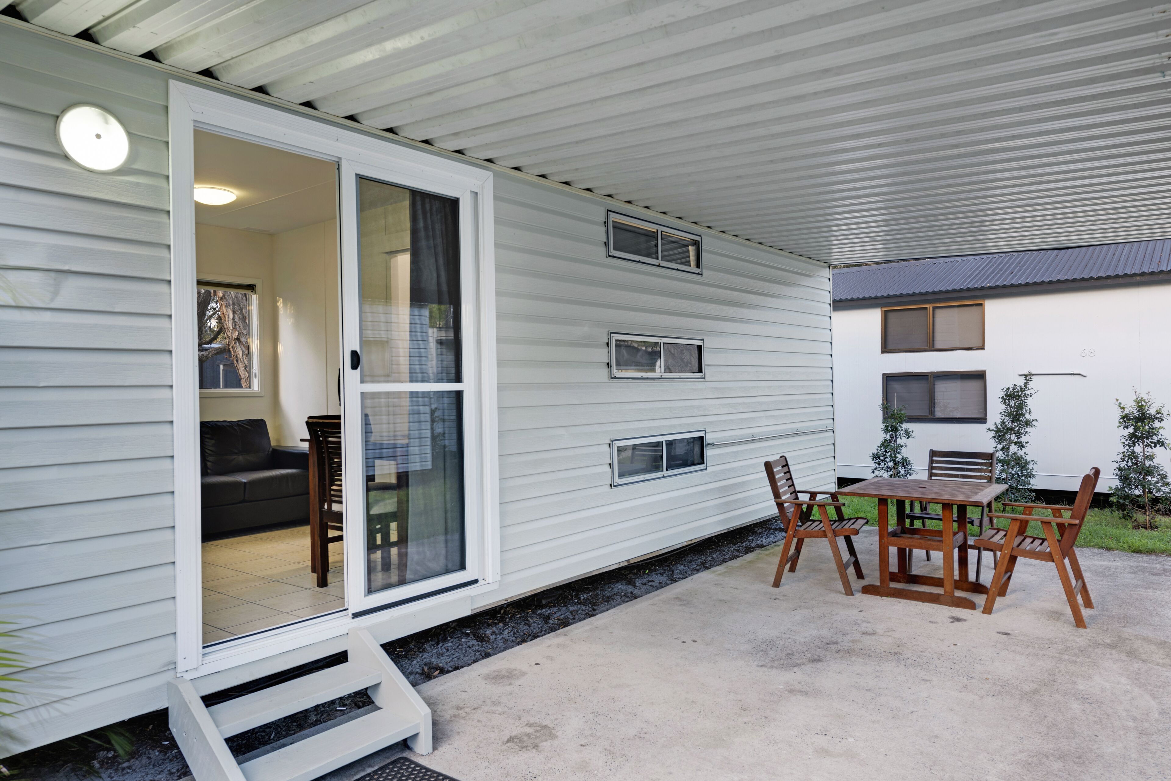 A covered patio with a table and chairs, a sliding glass door, and a small outdoor area with a step leading to the door.