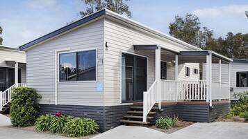 A single-story mobile home with a front porch, a small deck, and a number '277' sign.