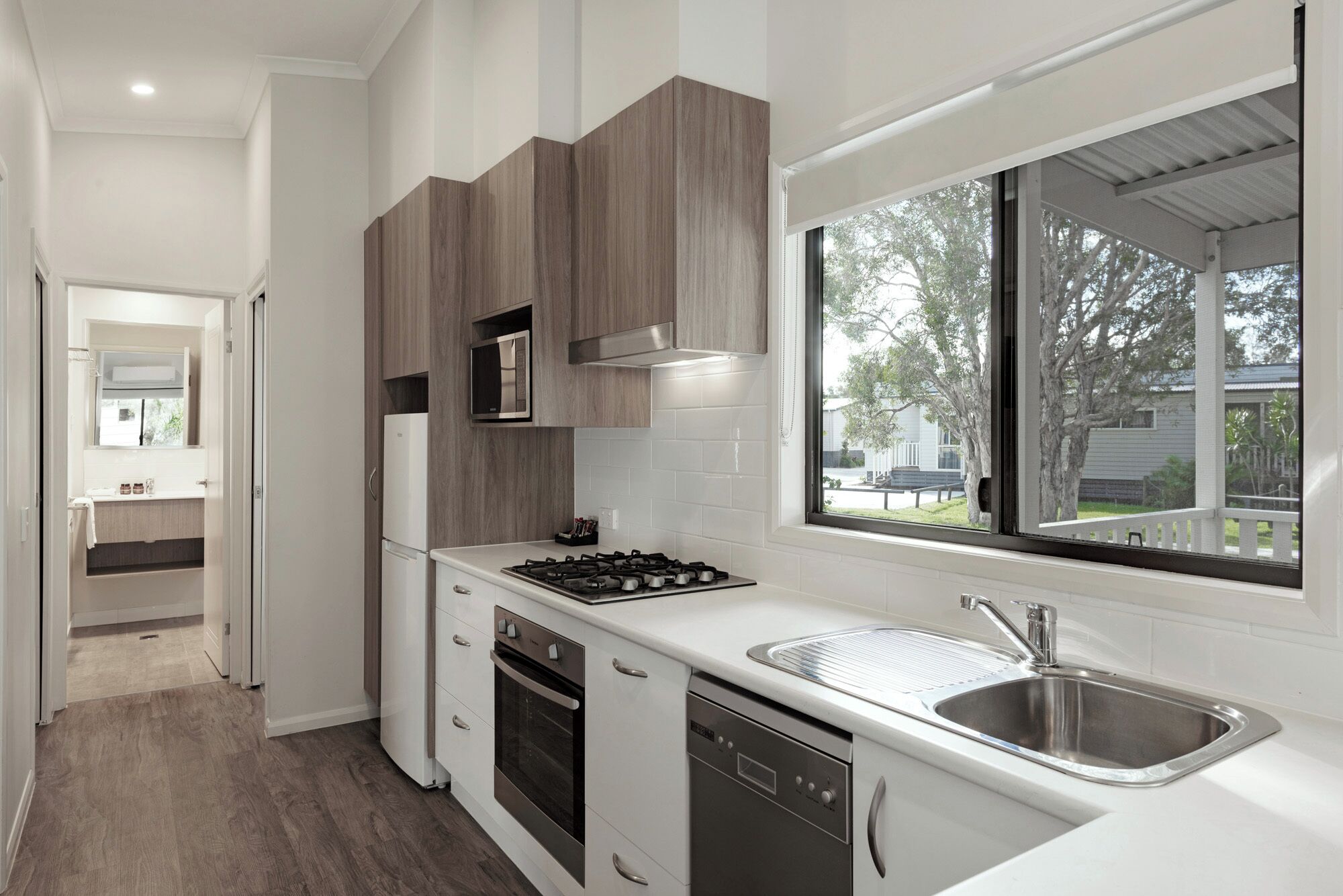 A modern kitchen with white cabinets, a stainless steel sink, and a window overlooking a backyard.
