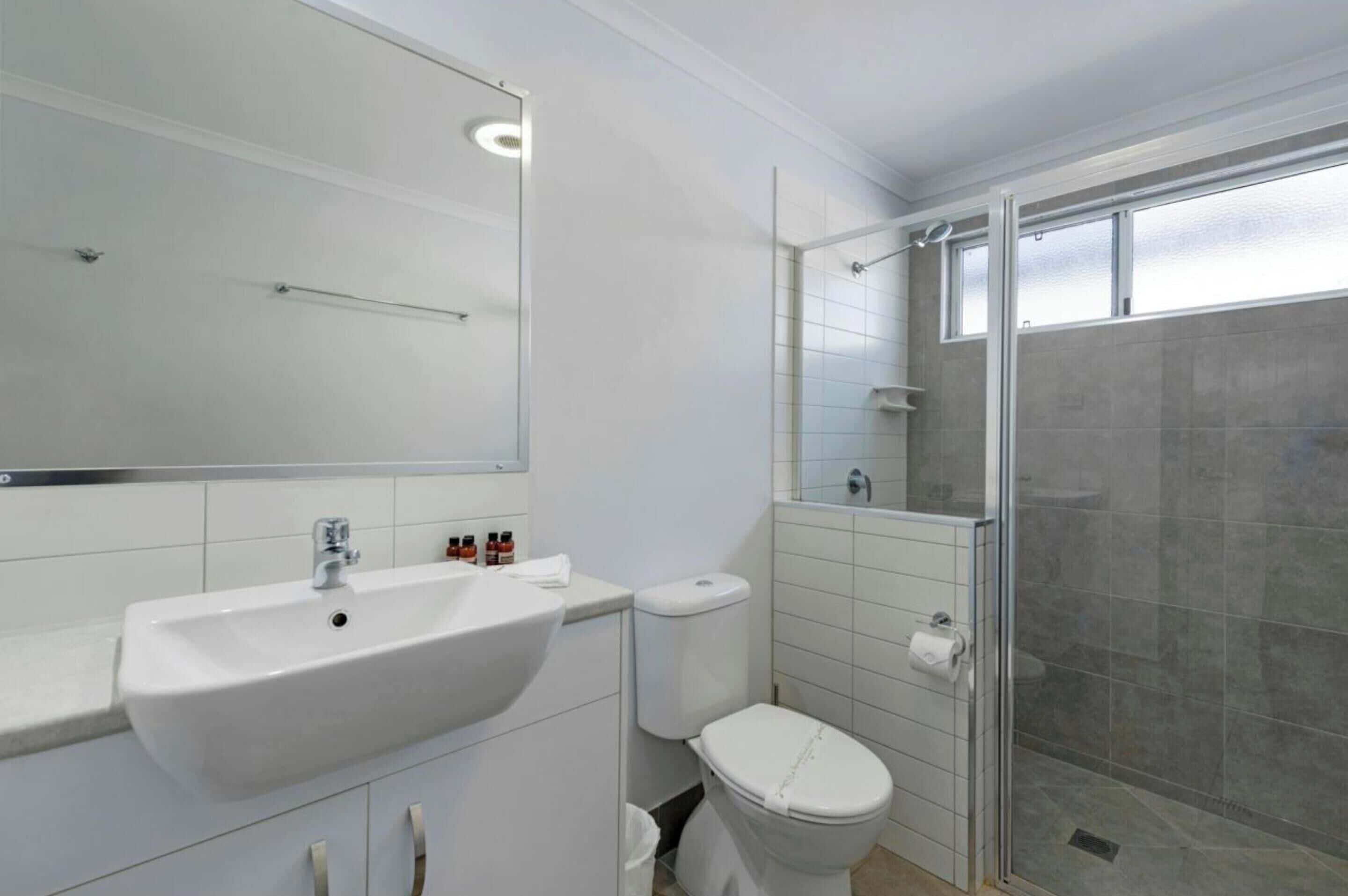 A modern bathroom with a white sink, toilet, and shower.