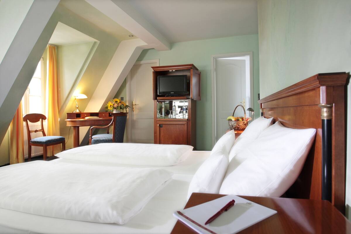 Habitación de hotel con dos camas, televisión, escritorio y una silla.