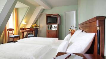 Een hotelkamer met twee bedden, een televisie, een bureau en een stoel.