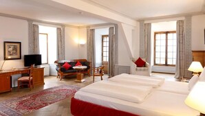 Una habitación de hotel con cama, escritorio, silla, sofá y televisor.
