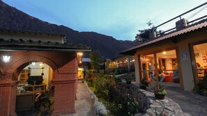 Un edificio con un arco de ladrillo en la entrada, un camino de piedra y un jardín con diversas plantas.
