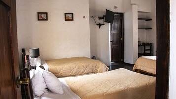 A hotel room with two beds, a flat-screen TV mounted on the wall, and a door leading to another room.