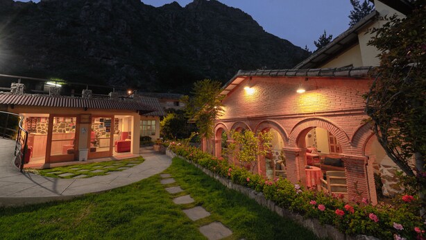 Un edificio tradicional con fachada de ladrillo, ventanas en arco y un pequeño jardín con piedras y flores.