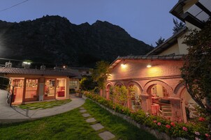 Un edificio tradicional con fachada de ladrillo, ventanas en arco y un pequeño jardín con piedras y flores.