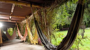 Una hamaca bajo una estructura de madera con vista al jardín.
