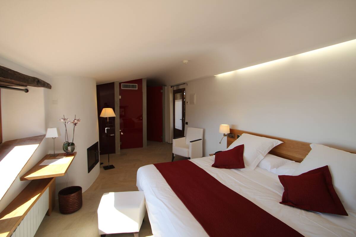 Quarto de hotel moderno com uma cama grande, mesas de cabeceira, uma escrivaninha e uma cadeira.
