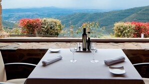Mesa para dos con vistas a un paisaje montañoso a través de una ventana enmarcada en piedra.