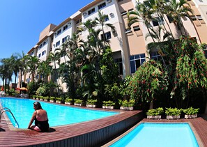 A hotel with a swimming pool, surrounded by palm trees and potted plants. - Lider Palace Hotel (Foz do Iguaçu)