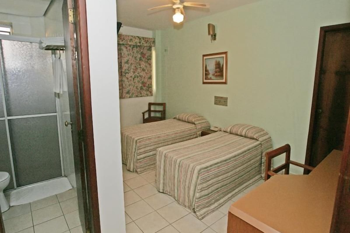 Habitación con dos camas, ducha, inodoro y ventilador de techo.