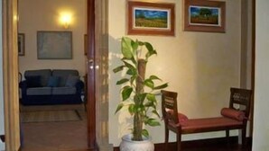 A living room with a sofa, a chair, a potted plant, and two framed pictures on the wall. - Marchese Sala (Agrigento)